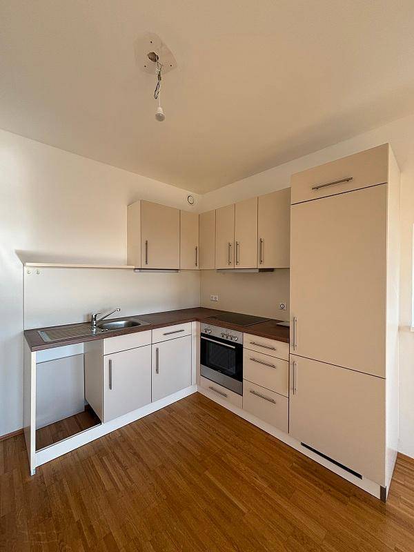 Funktionale Einbauküche in hellem Beige mit integrierten Geräten und Holzboden.