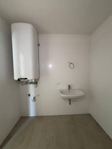 Modernes Badezimmer mit Waschbecken, Boiler und hellen Fliesen, bereit für die Installation.