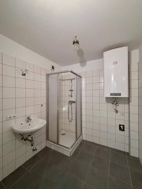 Badezimmer mit Duschkabine, Waschbecken und Wandfliesen in hellem Design.
