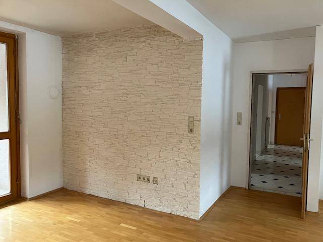 Geräumiges Zimmer mit Holzboden und einer strukturierten Wandverkleidung.