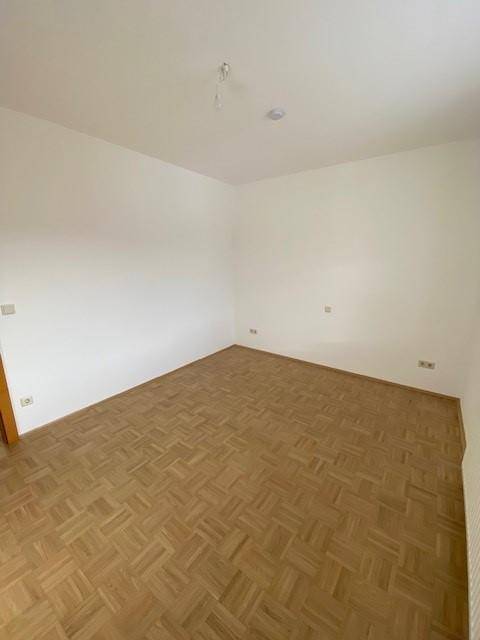 Leeres Zimmer mit Parkettboden und weißen Wänden, bietet eine neutrale Basis für die Einrichtung.