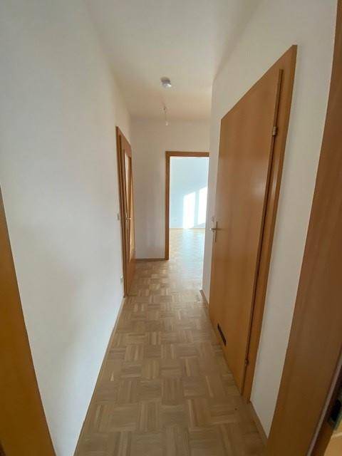 Langer Flur mit Parkettboden und Holztüren, der die verschiedenen Bereiche der Wohnung verbindet.