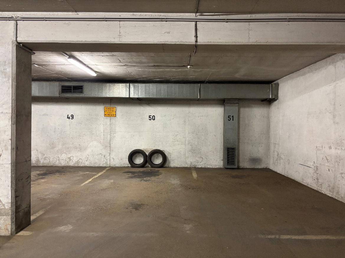 Innenansicht einer Tiefgarage mit nummerierten Stellplätzen und Betonpfeilern.