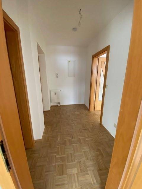 Geräumiger Flur mit Parkettboden und hellen Wänden, der zu verschiedenen Räumen führt.