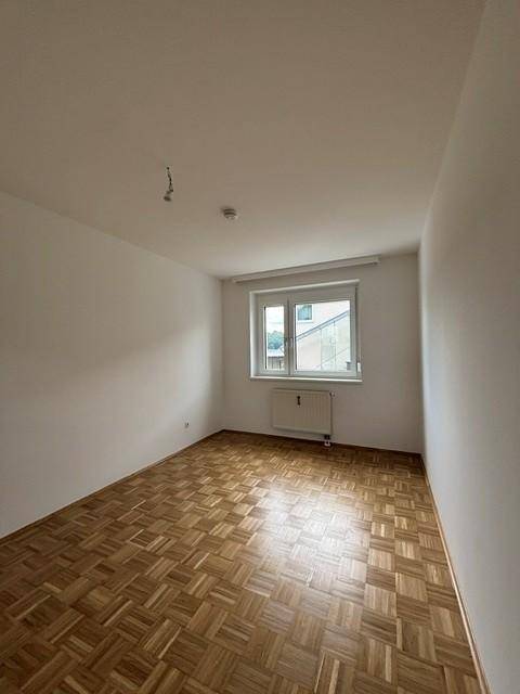 Freundliches Zimmer mit Parkettboden und einem Fenster, das für eine angenehme Helligkeit sorgt.