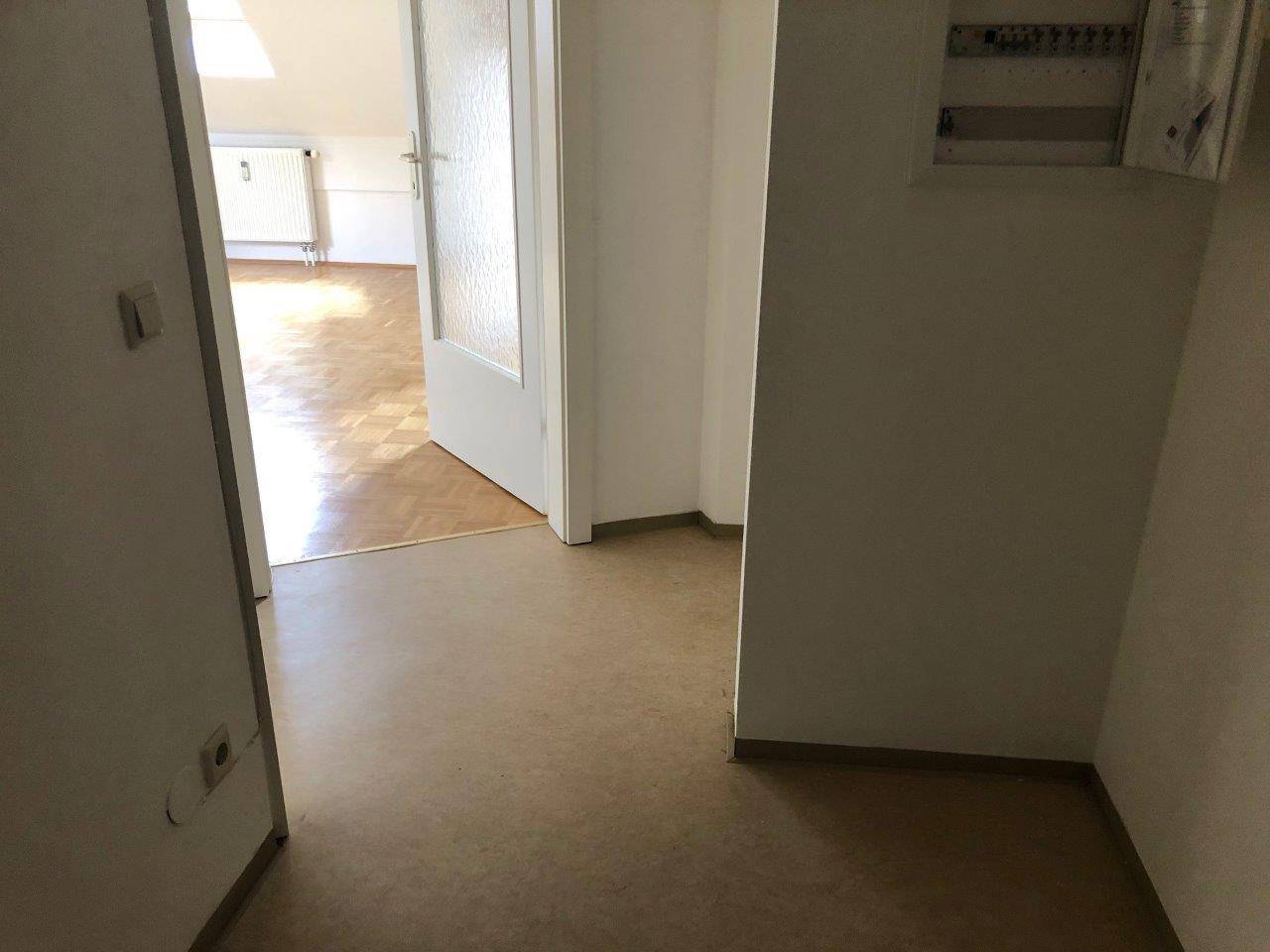 Flur mit Linoleumboden und Zugang zu weiteren Räumen, inklusive eines Sicherungskastens.