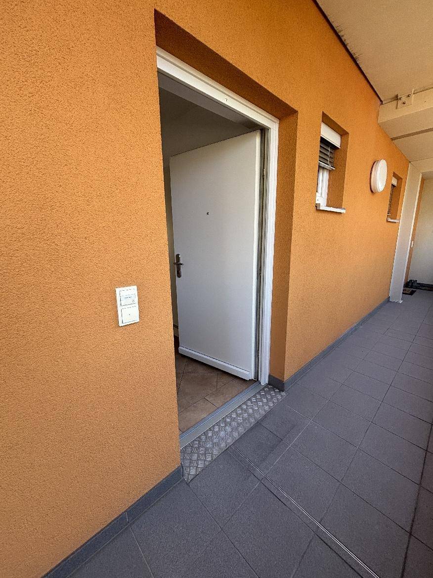 Eingangsbereich einer Wohnung mit orangefarbener Wand und gefliestem Boden im Mehrfamilienhaus.