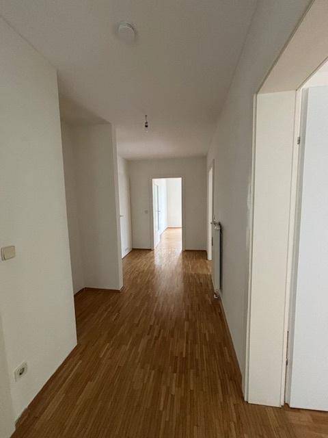 Langer Flur mit Parkettboden, der zu weiteren hellen Zimmern der Wohnung führt.