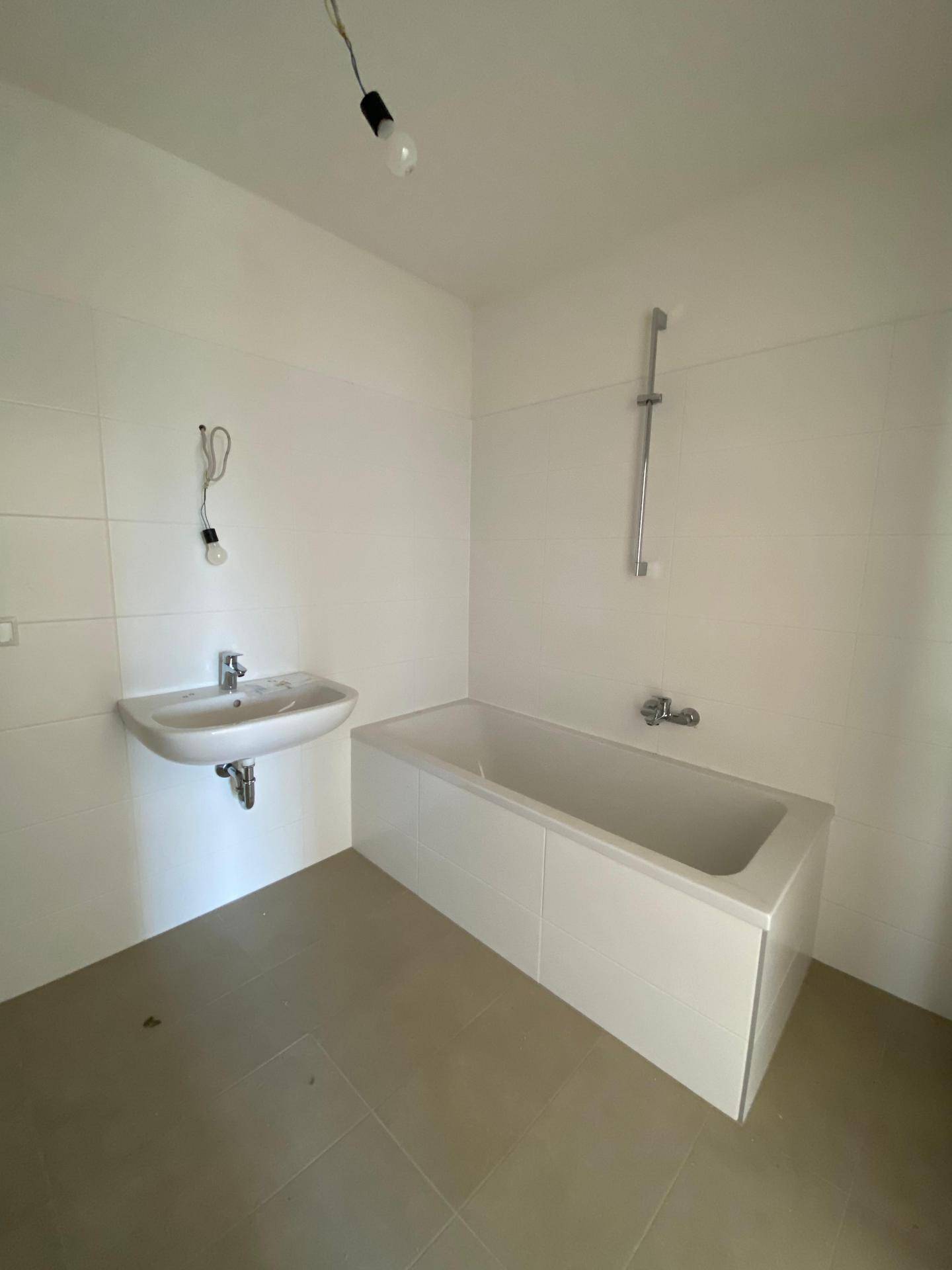 Modernes Badezimmer mit Badewanne und einem einzelnen Waschbecken, in hellen Farben gehalten.