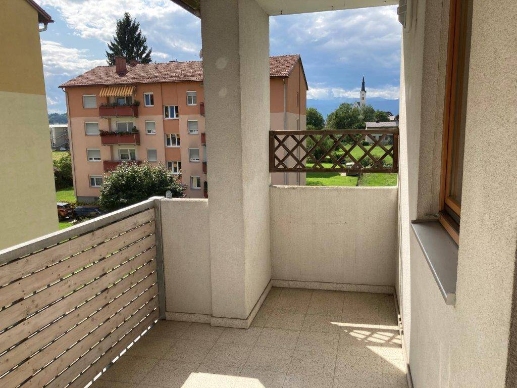 Balkon mit Holzelementen und Blick auf die umliegende Wohnbebauung und einen Kirchturm.