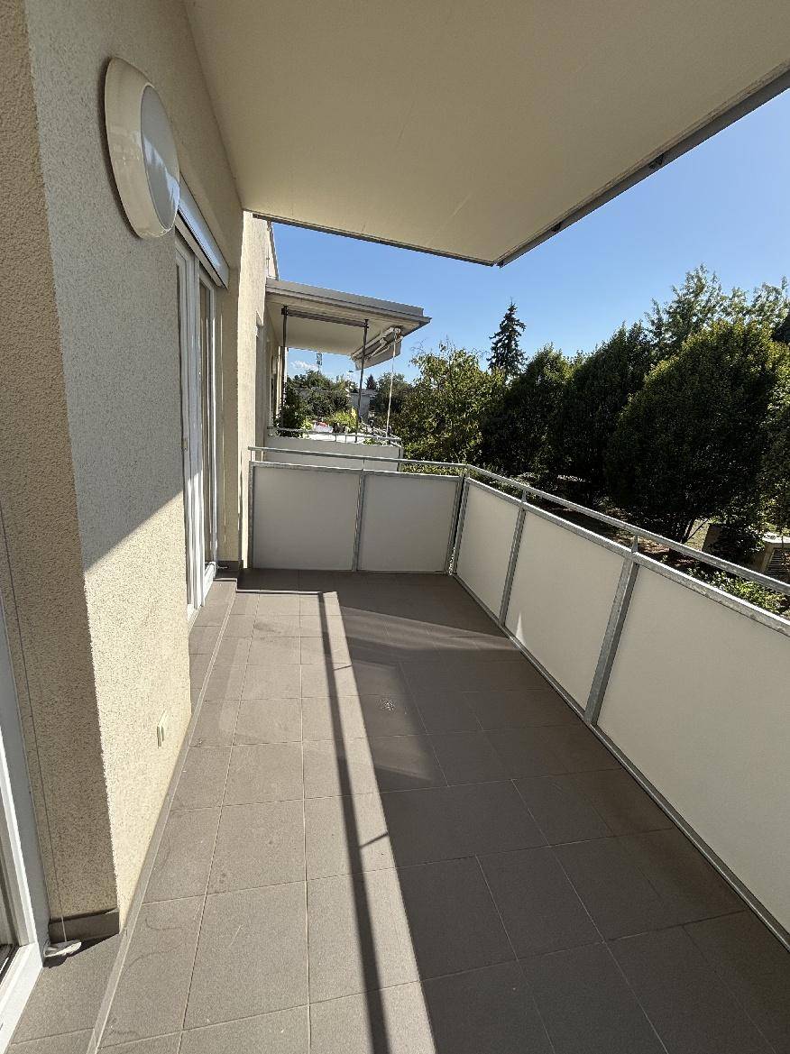 Heller Balkon mit Fliesenboden und angenehmem Blick ins Grüne.