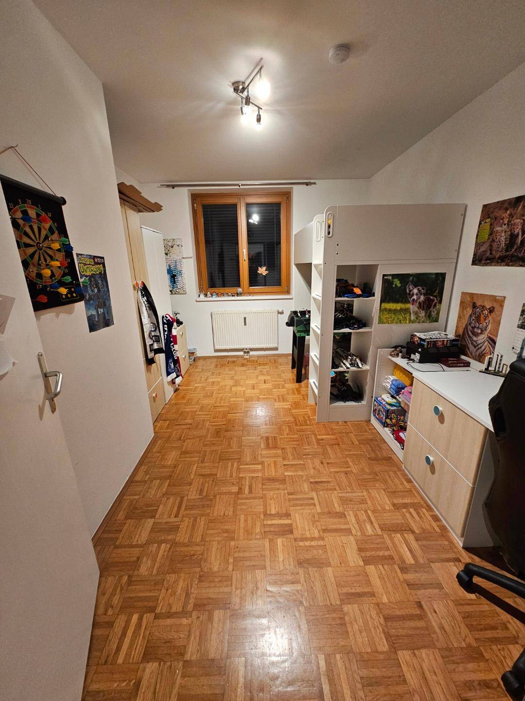 Kinderzimmer mit Hochbett, Schreibtisch und Parkettboden, hell durch Fenster.