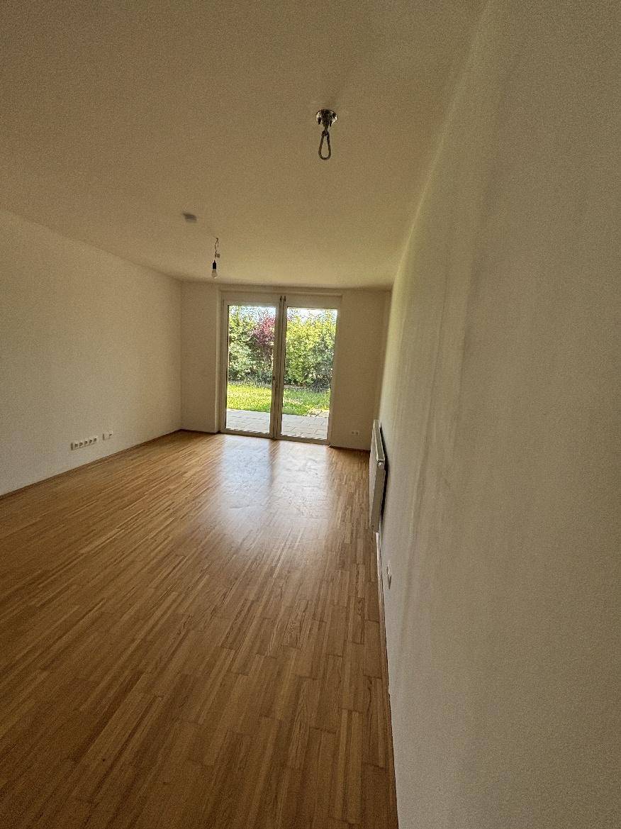 Lichtdurchflutetes Wohnzimmer mit Holzparkett und direktem Zugang zum Gartenbereich.