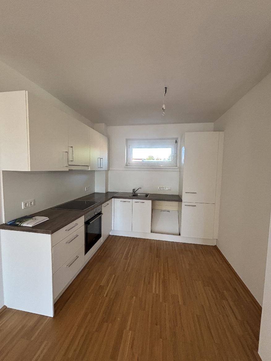 Moderne Einbauküche mit weißen Schränken, dunkler Arbeitsplatte und Fenster, bereit zur Nutzung.