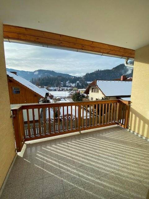 Balkon mit Holzbalken und Fliesenboden bietet einen weiten Blick auf die verschneite Berglandschaft.