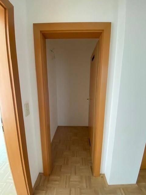 Kleiner Abstellraum oder Nische mit Parkettboden und weiß gestrichenen Wänden.