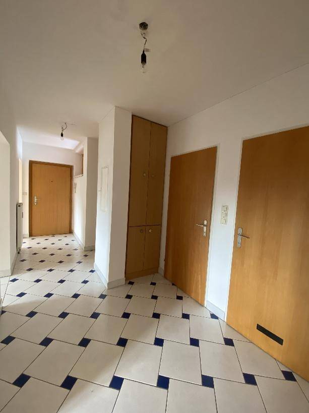 Geräumiger Eingangsbereich mit Fliesenboden und mehreren Holztüren.