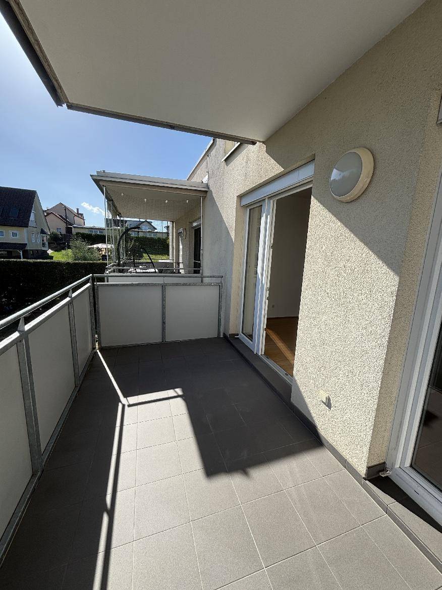 Heller Balkon mit Fliesenboden und Metallgeländer, bietet Platz für Entspannung im Freien.