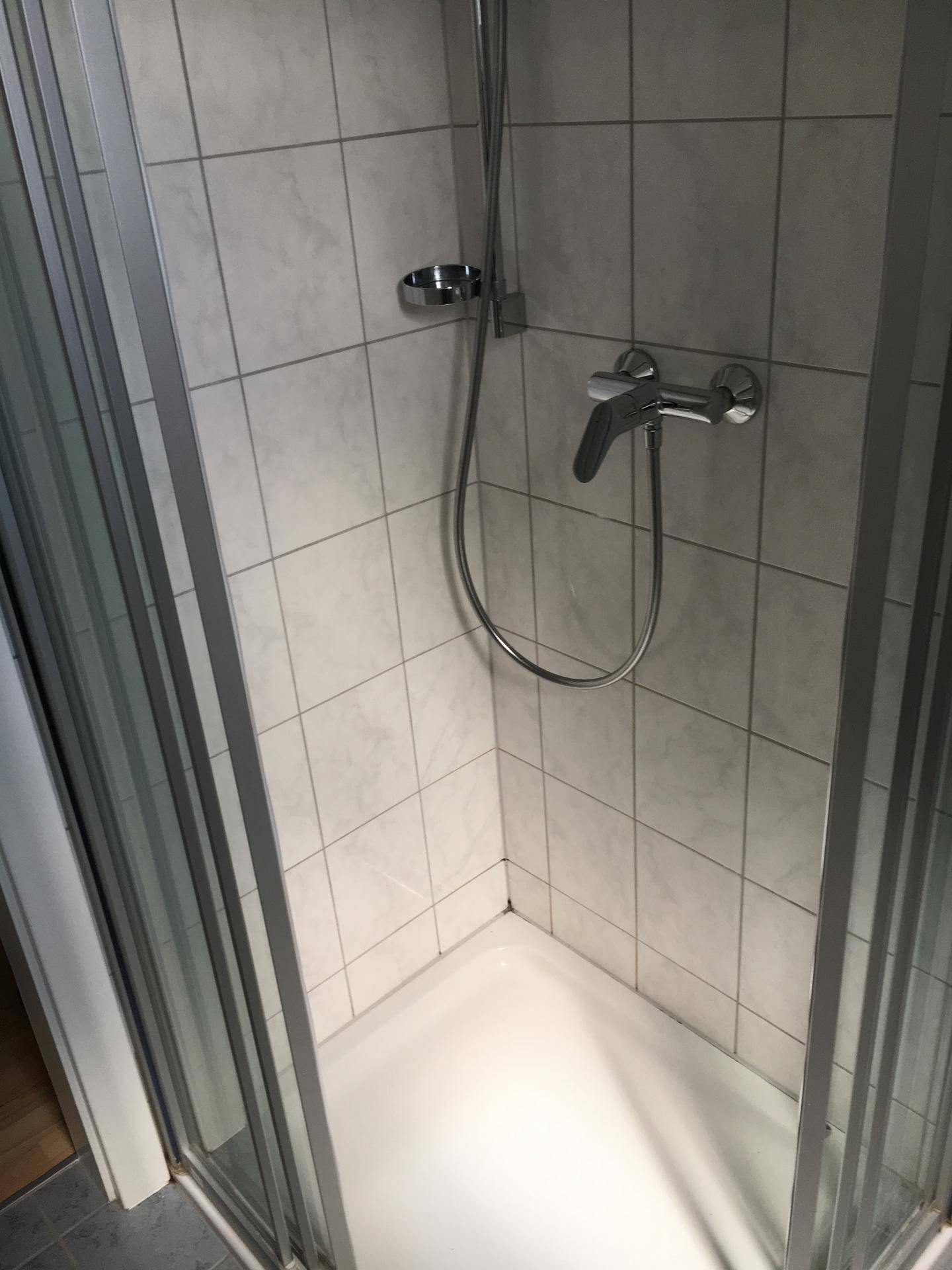Duschkabine mit weißen Fliesen und moderner Armatur in einem Badezimmer.