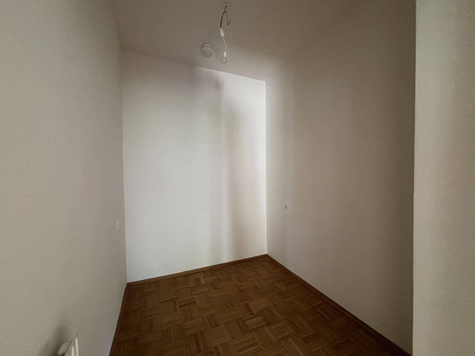 Heller, leerer Raum mit Parkettboden und weißen Wänden, vielseitig nutzbar in der Wohnung.