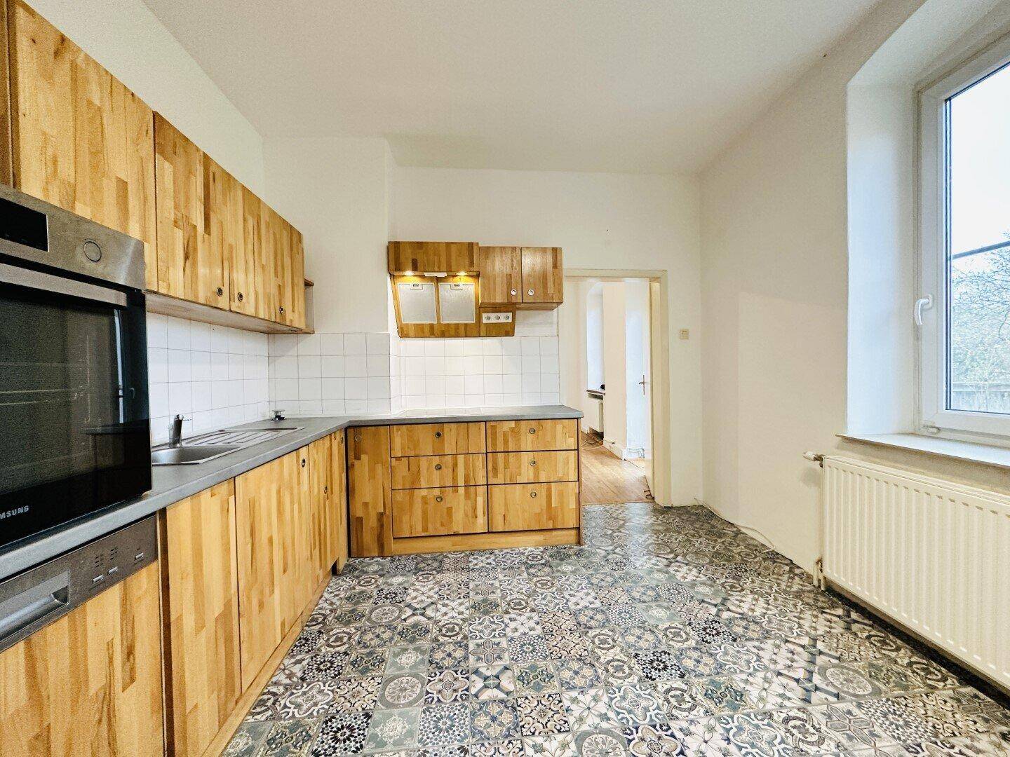 Geräumige Küche mit Holzelementen, funktionalen Geräten und einem Fenster für natürliches Licht.
