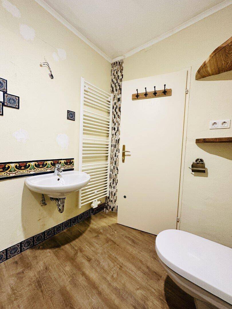 Badezimmer mit Waschbecken, Toilette und beheiztem Handtuchhalter, bereit zur Nutzung.