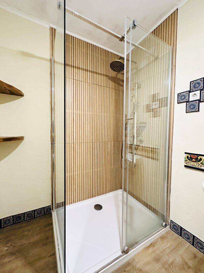 Duschbereich mit Glasabtrennung und vertikalen Holzpaneelen an der Wand.