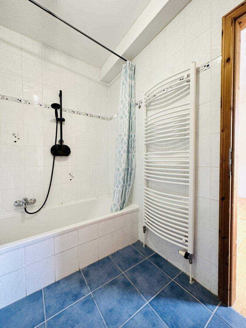 Badezimmer mit Badewanne, blauen Fliesen und einem beheizten Handtuchhalter.