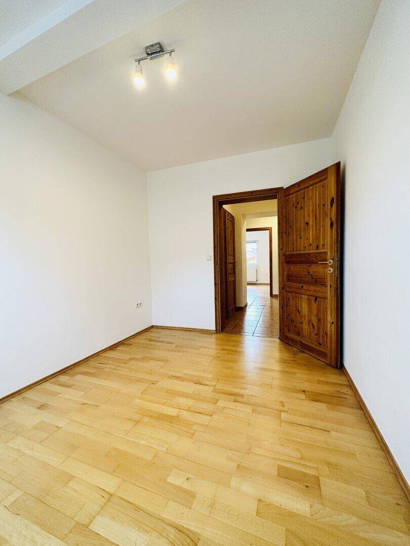 Schlafzimmer mit Laminatboden und einer Holztür, die zu einem anderen Raum führt.
