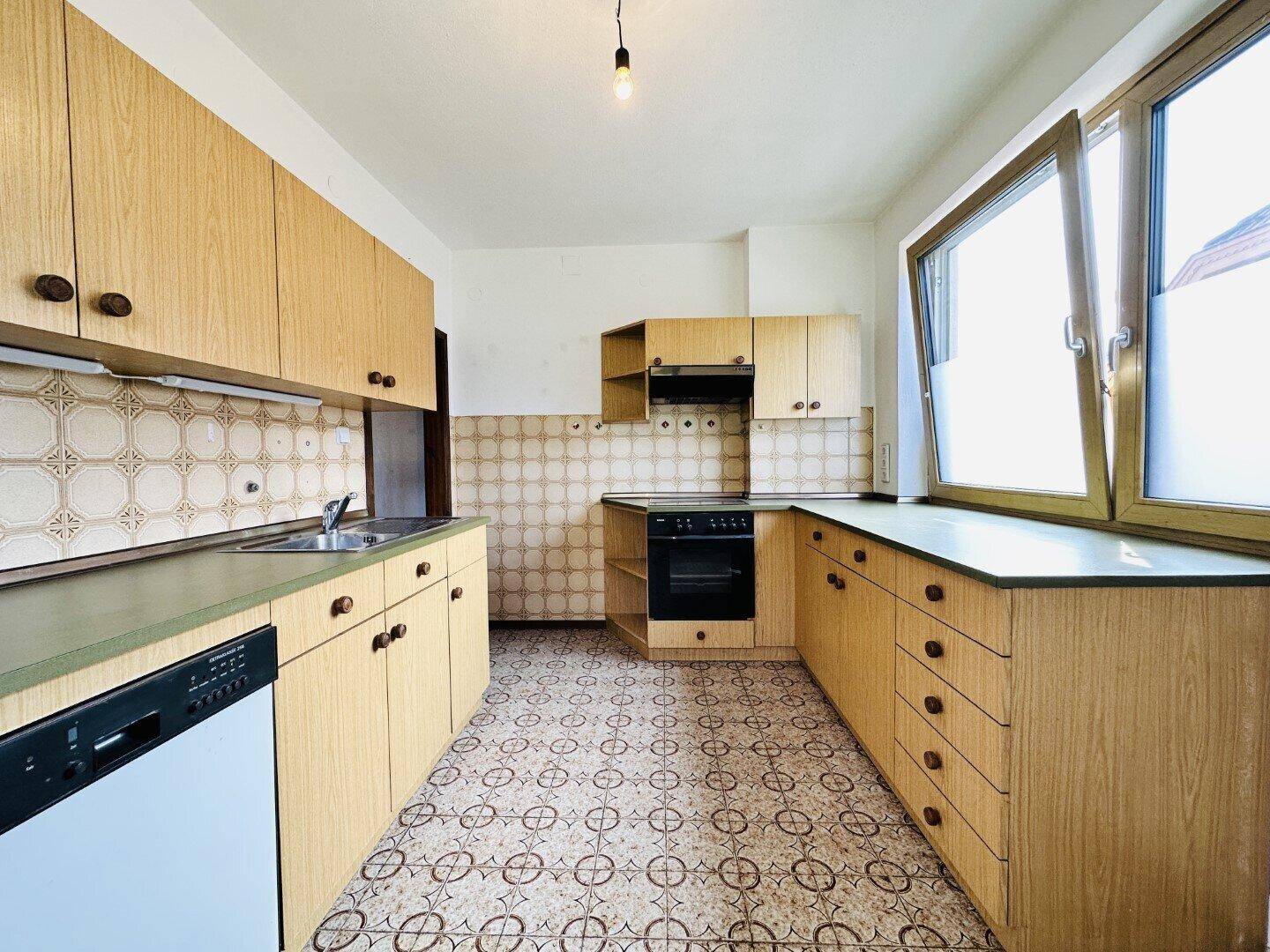 Küche im traditionellen Stil mit Holzschränken, Fliesenrückwand und Fenster.