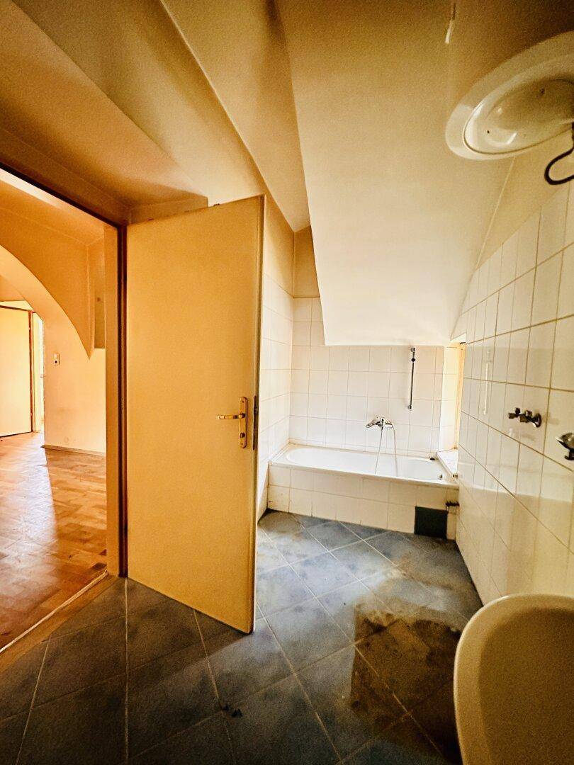 Badezimmer mit Badewanne und Fliesen, das eine umfassende Modernisierung benötigt.