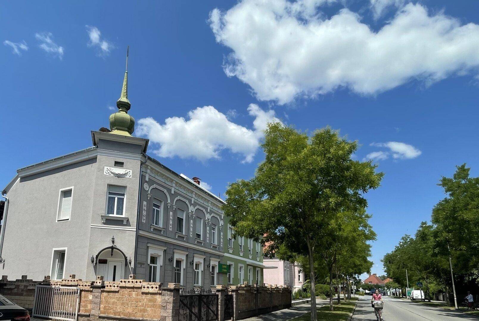 Historisches Gebäude mit Turm und dekorativer Fassade unter blauem Himmel mit Wolken.
