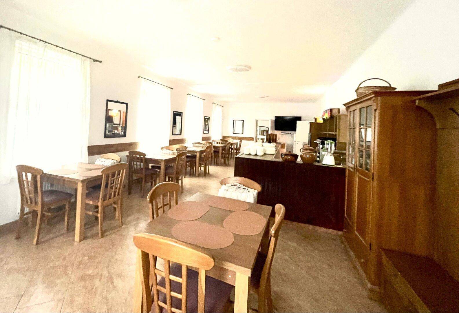 Großer Esssaal mit vielen Holztischen und Stühlen, ideal für Gruppen, mit einem Buffetbereich.
