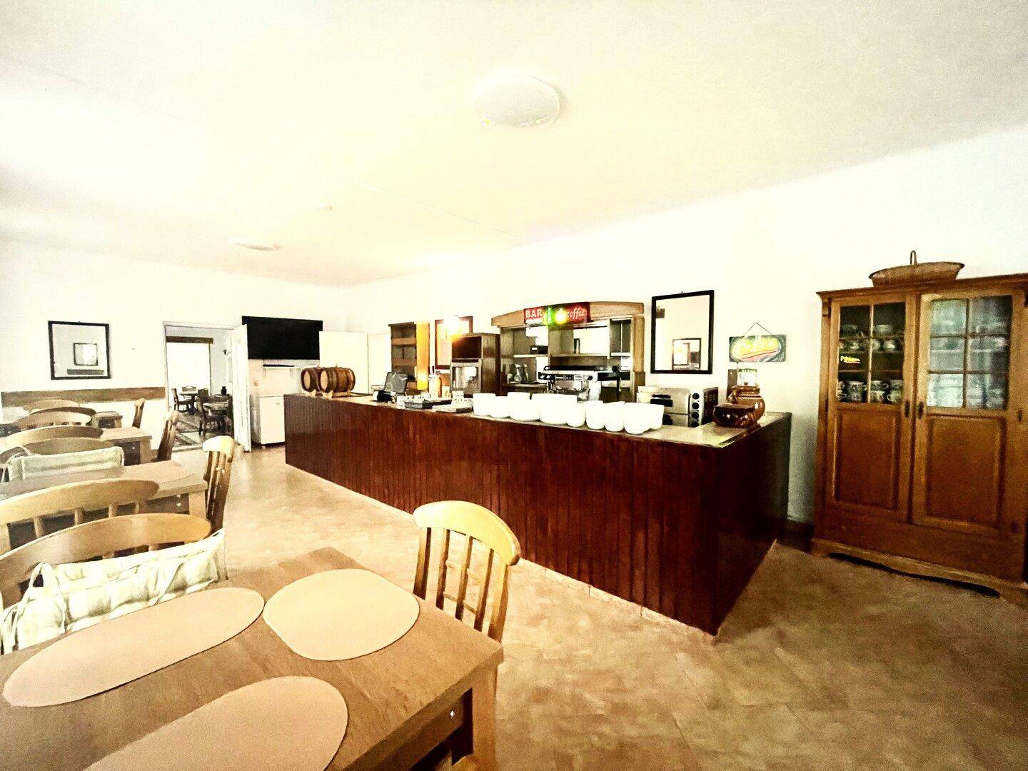 Buffet- und Barbereich mit Holztresen, Geschirr und traditionellen Holzmöbeln in einem hellen Raum.