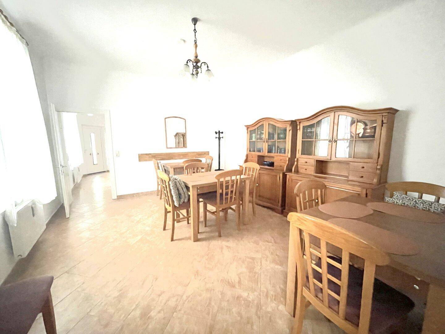 Gemütlicher Essbereich mit Holztischen, Stühlen und traditionellen Schränken in einem hellen Raum.