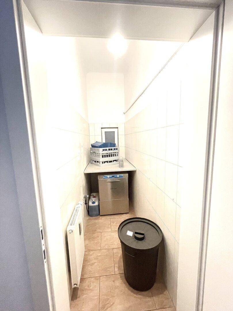 Kleiner Hauswirtschaftsraum mit Waschmaschine, Heizkörper und Fliesenboden.