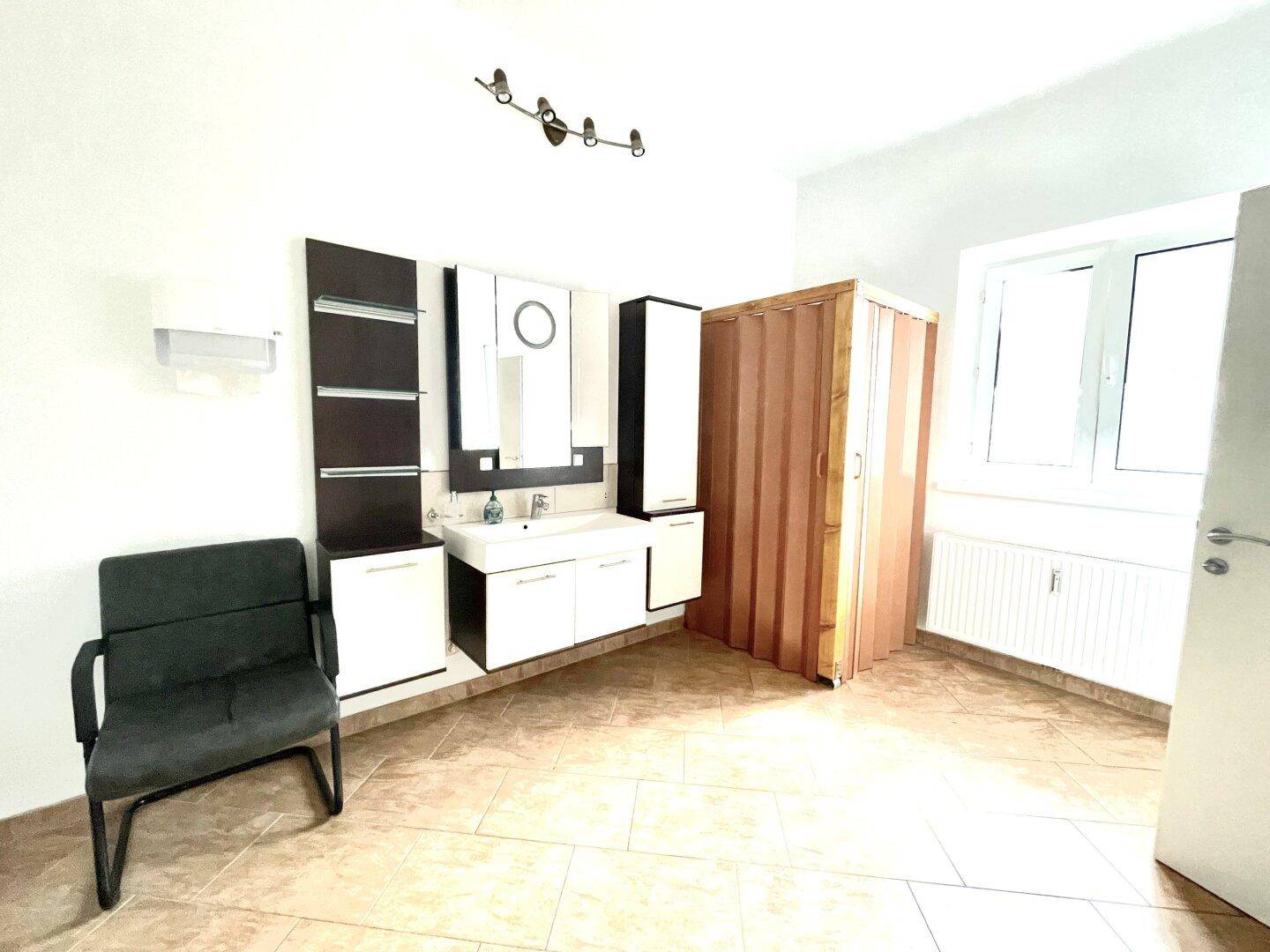 Großes Zimmer mit Waschtischmöbeln, Fenster und Heizkörper, möglicherweise ein Badezimmer.