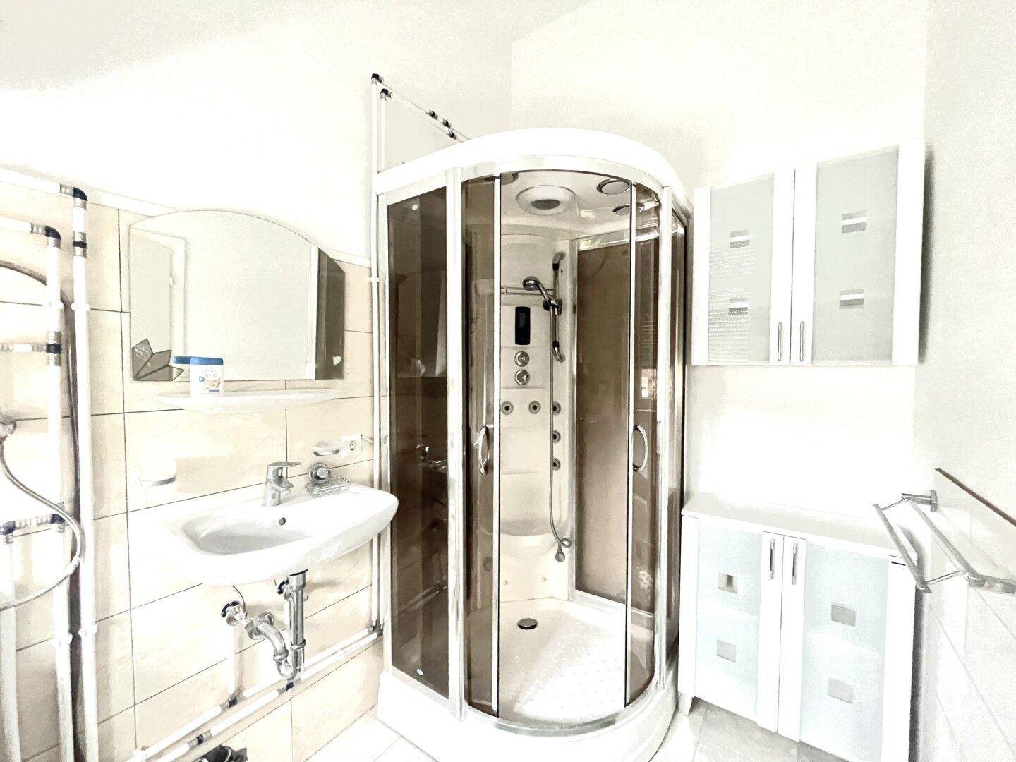 Kleines Badezimmer mit Duschkabine, Waschbecken und Spiegelschrank, funktional eingerichtet.