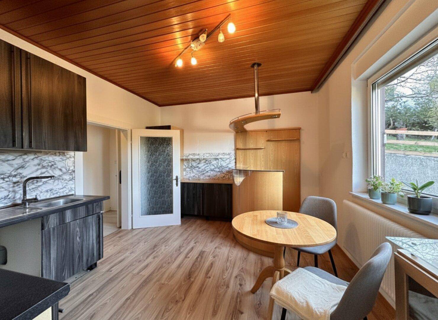 Helle Küche mit Essbereich, Holzdecke und funktionalen Einbauschränken.