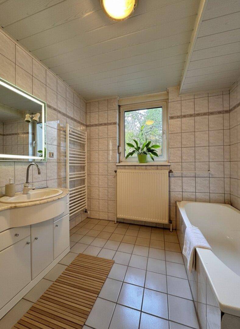 Helles Badezimmer mit Badewanne, Fliesenboden und Fenster für natürliche Belüftung.