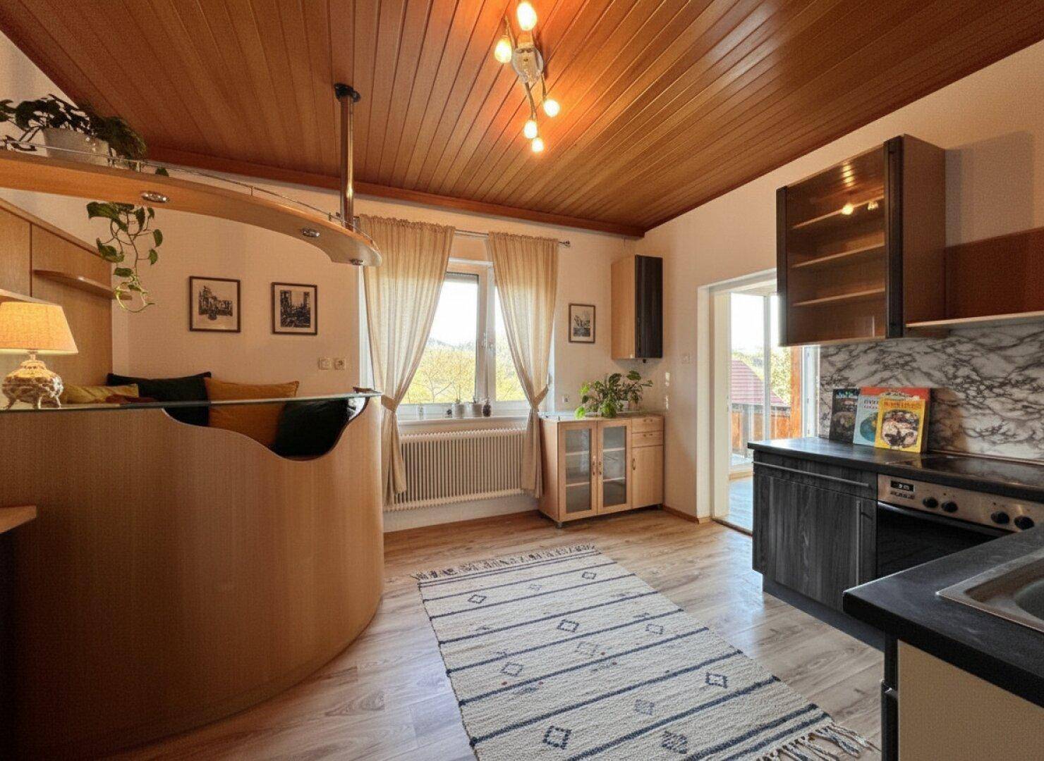 Gemütliche Küche mit Holzdecke, integrierter Bar und Blick ins Grüne.