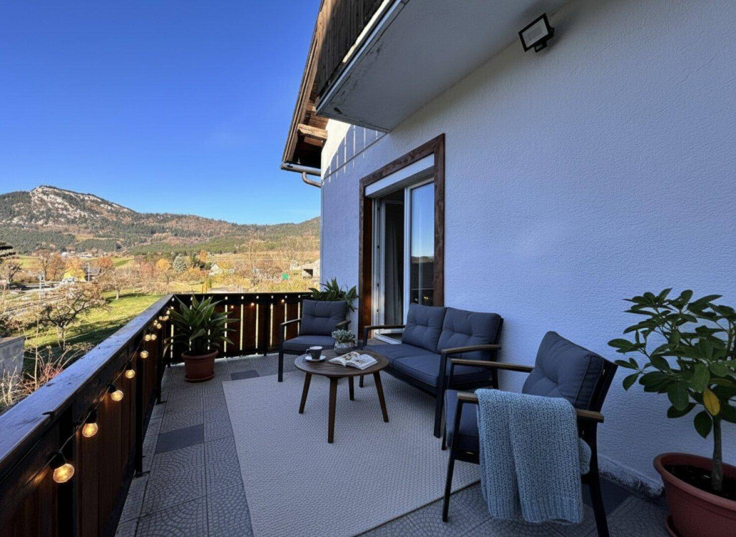 Sonniger Balkon mit Sitzgelegenheiten und herrlichem Blick auf die umliegenden Berge.