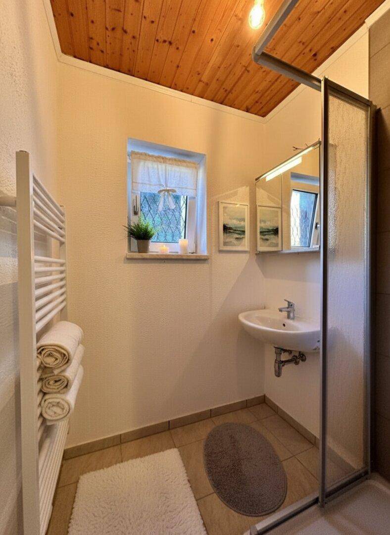Funktionales Badezimmer mit Dusche, Fenster, Einzelwaschbecken und Holzpaneeldecke.