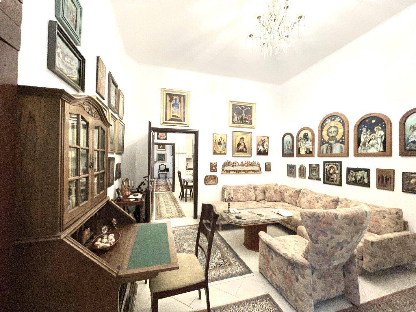 Gemütliches Wohnzimmer mit großem Ecksofa und Couchtisch, reich verziert mit religiösen Kunstwerken.