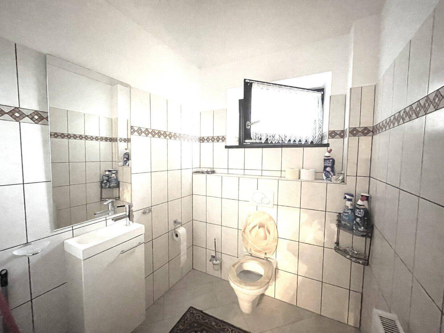 Kleines Gäste-WC mit Waschbecken und Toilette, komplett gefliest und funktional eingerichtet.