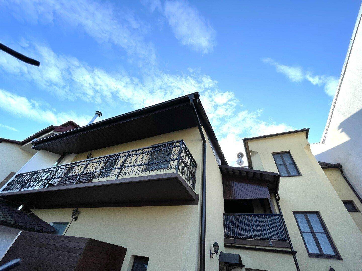 Fassade des Gebäudes mit mehreren Balkonen und traditionellen Geländern unter blauem Himmel.
