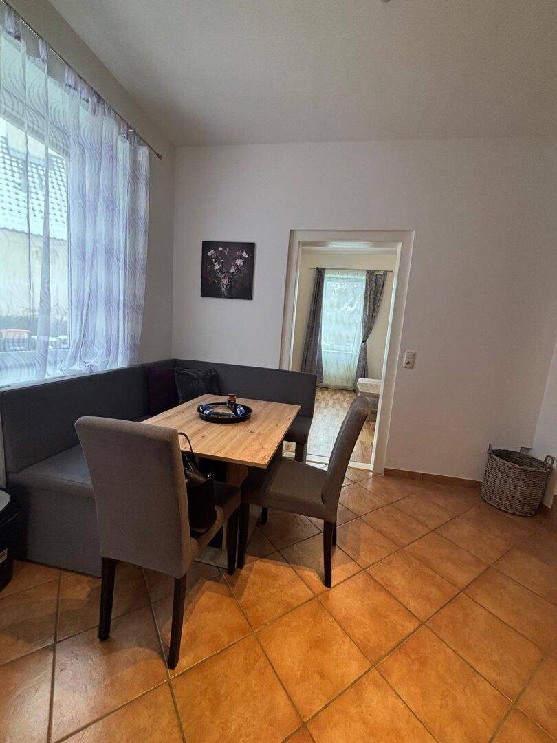 Gemütlicher Essbereich mit Eckbank, Holztisch und Terrakottafliesen.