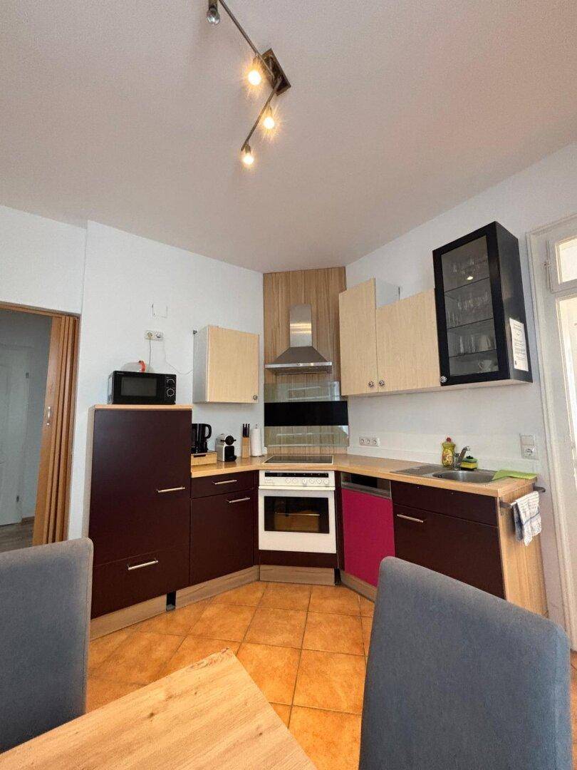Küche mit modernen Geräten, Terrakottafliesen und einem Essbereich im Vordergrund.