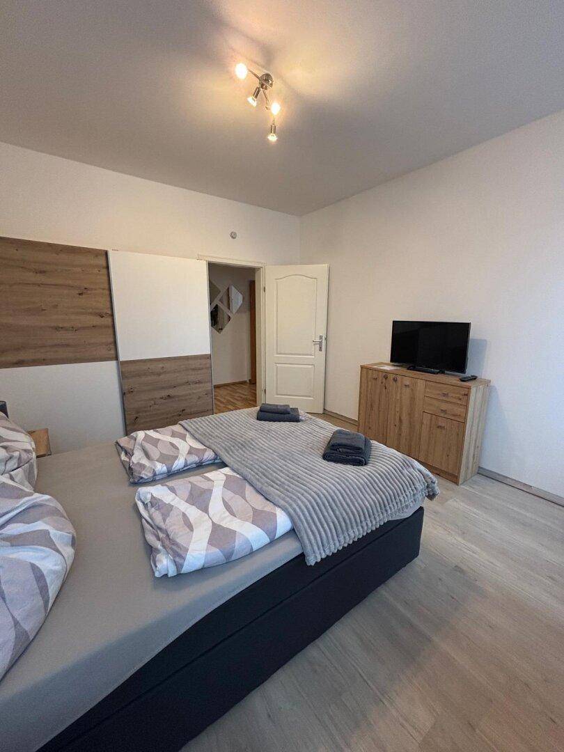 Modern eingerichtetes Schlafzimmer mit Doppelbett, Schrank und Laminatboden.
