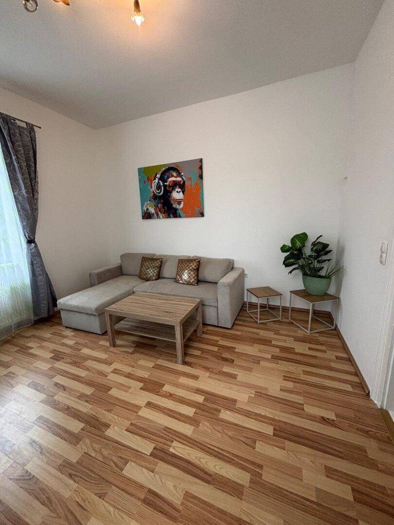 Gemütliches Wohnzimmer mit Sofa, Couchtisch und Laminatboden.